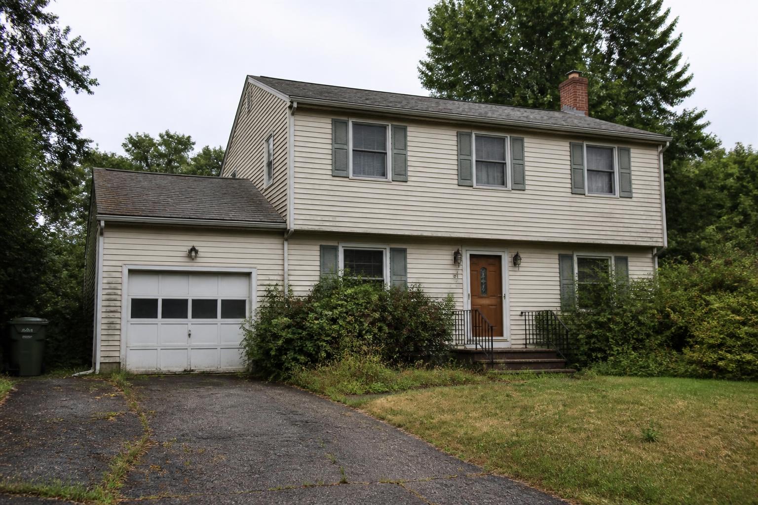 Dated suburban house with overgrown landscaping before renovation